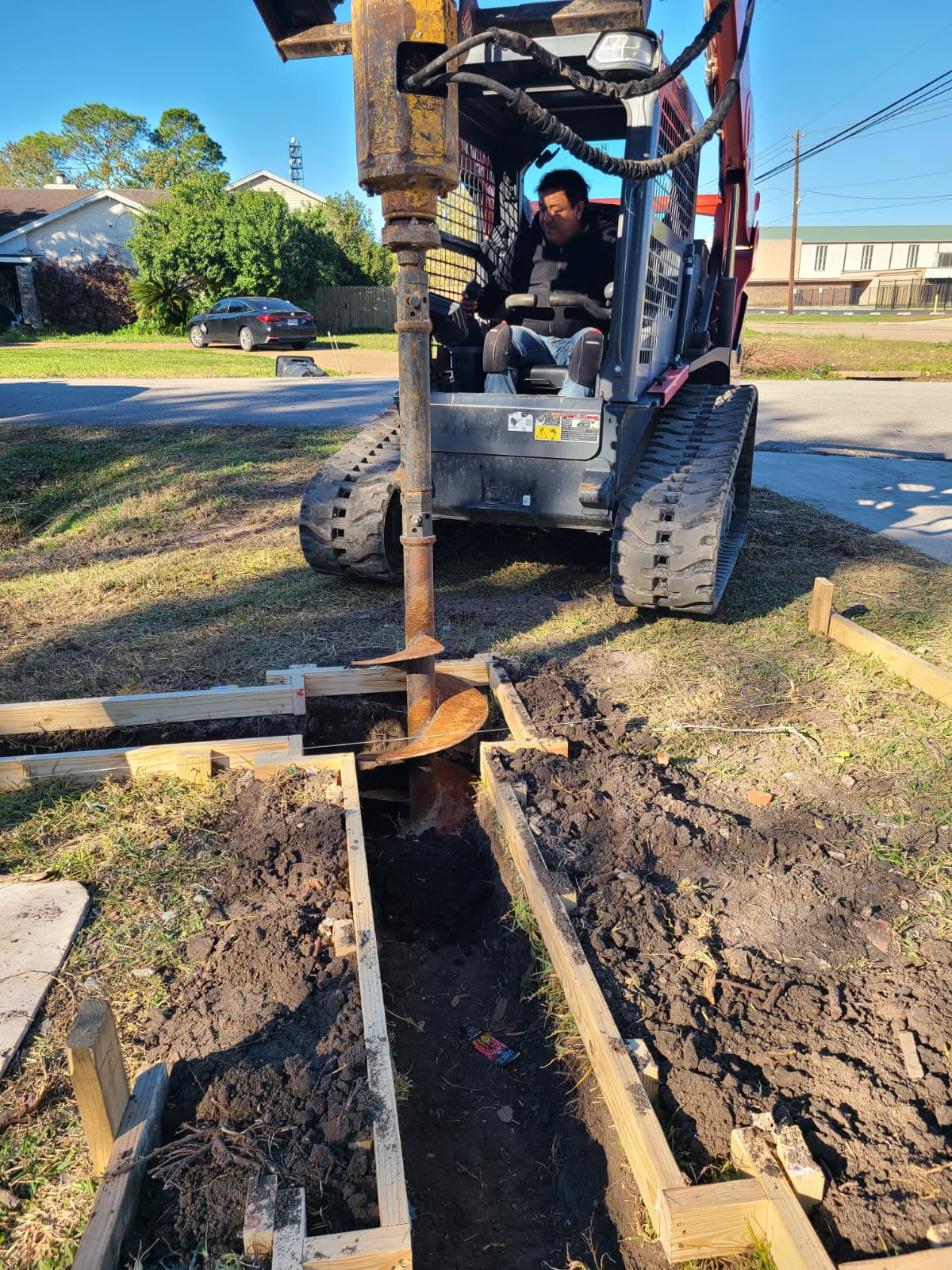 Skid steer with auger drilling pier for concrete footing in Houston